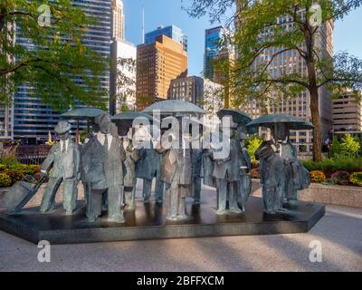 The Living World Series Gentlemen Statue by Taiwanese sculptor Ju Ming This artwork is prominently displayed on the Chicago AMA Plaza. The Gentlemen are part of Ju’s “Living World Series,” featuring eleven bronze plated figures draped in trench jackets and holding umbrellas. Blocky and minimalist, the figures are reduced to the basic forms intentionally to embrace the inner spiritual qualities within human bodies. Stock Photo