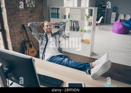 Photo of business guy ignoring working computer monitor legs on table lazy secretary hands behind head doing nothing boredom wear casual shirt sit Stock Photo