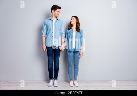 Full length photo of positive passionate students woman man spouses hold hand look good enjoy togetherness wear casual style clothes sneakers isolated Stock Photo