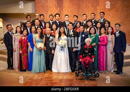 A Vietnamese American wedding group in traditional dress pose for a group photo after the ceremony at a Southern California Catholic church. Stock Photo