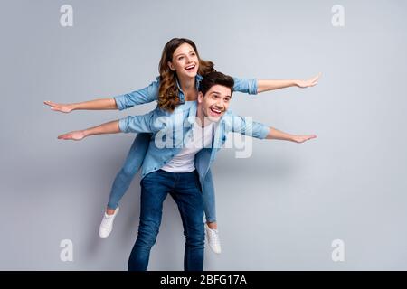 I will show you sky. Portrait of positive cheerful man hold his girlfriend piggyback imagine fly like airplane wear casual style clothes isolated over Stock Photo