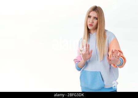 I dont like it. Portrait of disappointed, unsatisfied blonde girl stay away, raising hands in stop, rejection, cringing from bad idea, refuse to Stock Photo