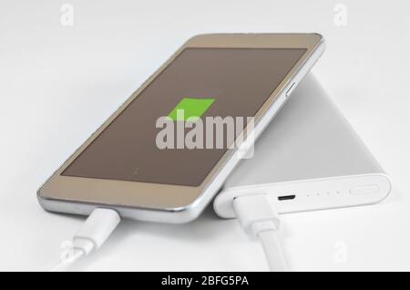 Close-up of  empty smartphone battery recharging  from powerbank  on  white background. External solute for charging devices for travel . Stock Photo