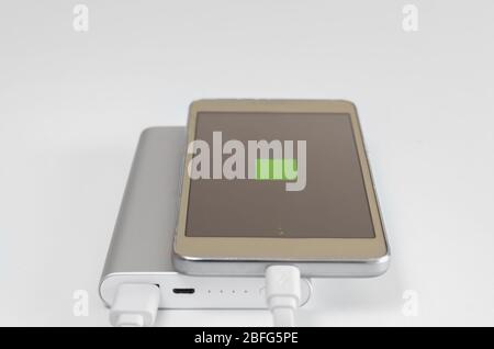Display with sign of  recharging smartphone battery recharging  from powerbank  on  white background. External solute for charging devices for travel Stock Photo