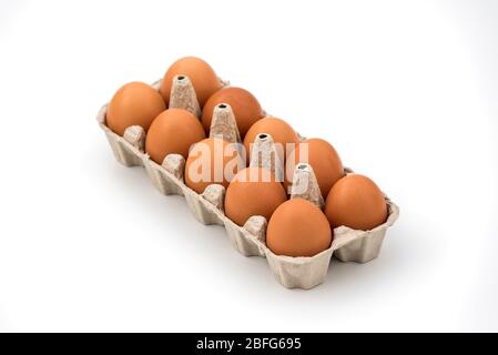 Chicken eggs in cardboard egg box on white background. Raw chicken eggs in open egg box on a white background. Eggs in the package. Stock Photo