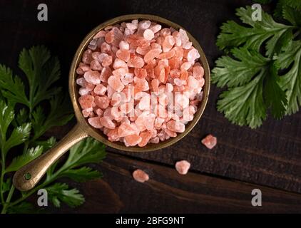 Overhead view of pink Himalayan sea salt with fresh cilantro on a wooden surface Stock Photo