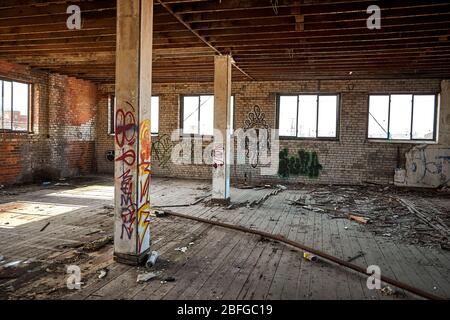 Photograph of interior of abandoned building in Detroit Michigan showing evidence of homeless and graffiti spray painted on walls Stock Photo