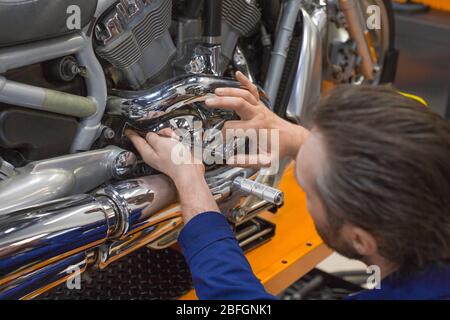 A close up view of a man repairing one of the mechanisms of a motorcycle. Stock Photo