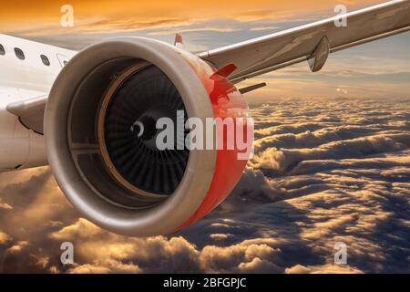 Aviation concept showing closeup of airplane wing flying above golden sunset clouds with copy space. Concept of travel by air for business or leisure. Stock Photo