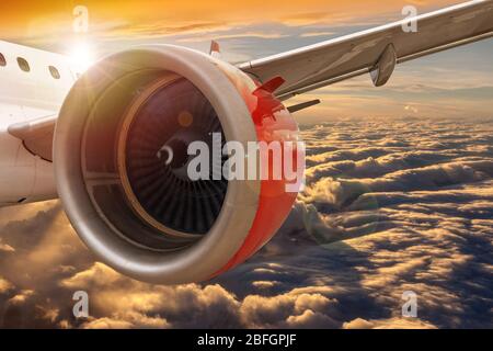 Aviation concept showing closeup of airplane wing flying above golden sunset clouds with copy space. Concept of travel by air for business or leisure. Stock Photo