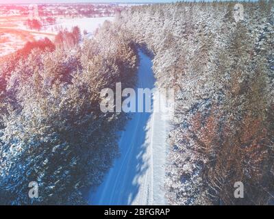 Country road in a pine forest. Winter nature. Snowy forest. View from above. Stock Photo