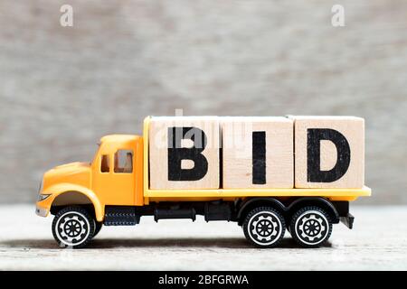 Truck hold letter block in word bid on wood background Stock Photo