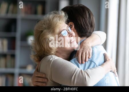 Loving elderly mother cuddles adult son family enjoy reunion indoors Stock Photo