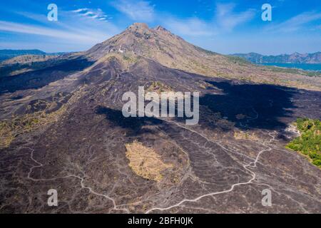 Aerial view of solidified black volcanic lava flows around the slopes of an active volcano.  (Mount Batur) Stock Photo