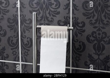 Empty toilet roll on a holder in a bathroom.  Panic buying during lockdown concept.  With tiles in the background Stock Photo