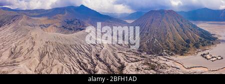 Panoramic aerial view of the Mount Bromo active volcano and Mount Batok cider cone next to the 'sea of sand' in Java, Indonesia Stock Photo