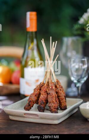 Chicken satay is served in a unique way on a wooden table. Stock Photo