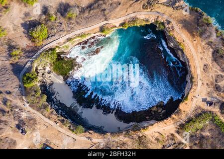 Top down aerial view of waves from a tropical ocean breaking inside a round, enclosed bay (Broken Beach, Nusa Penida) Stock Photo