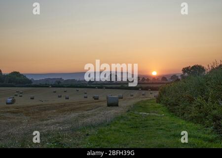 Cut wheat field in Herefordshire countryside with bails towards Hay Fluff at sunset Stock Photo