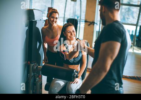 Pretty young woman having exercises on leg extension and leg curl machine in the gym Stock Photo