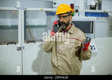 Portrait of mature industrial man engineer with smartphone in a factory Stock Photo