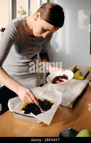 Woman decorating a berry jam pie. Female decorating cake with blueberries, movement hands Stock Photo