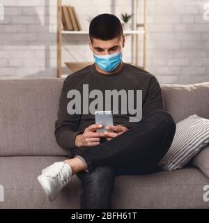 Man wearing surgical mask using smart phone Stock Photo