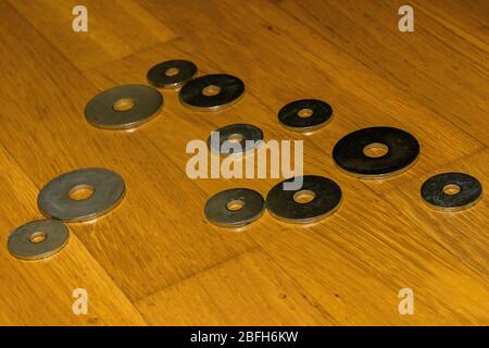 close-up image of iron washers of various sizes placed in bulk on a light parquet floor Stock Photo