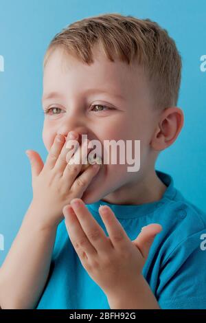 Little Boy Holding and eating an Banana on blue background, food, diet and healthy eating concept Stock Photo