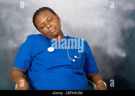 young woman doctor in blue blouse sitting at office tired and sleeping Stock Photo