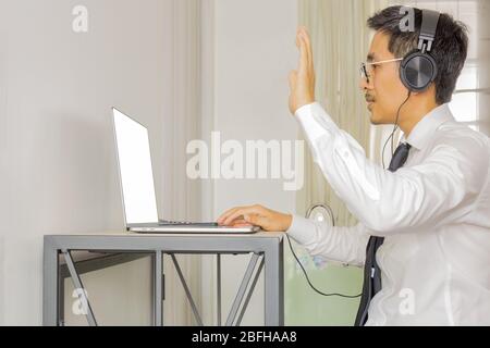Bsinessman with headphone making video conference on with laptop. Stock Photo
