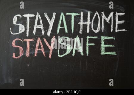 Inscription stay at home stay safe. Outbreak Warning. written white chalk on blackboard in connection with epidemic of coronavirus worldwide. Covid 19 Stock Photo