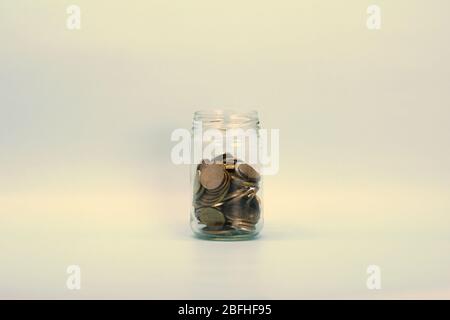 Metal coins, Russian rubles, lie in a transparent glass jar on a light background. Place for text and design. Stock Photo