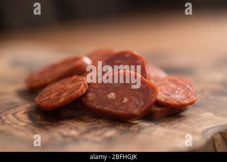 Slices of chorizo on olive wood board Stock Photo