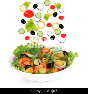 Fresh mixed vegetables falling into bowl of salad isolated on white Stock Photo