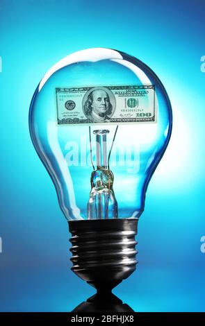 Light bulb with dollar on blue background Stock Photo