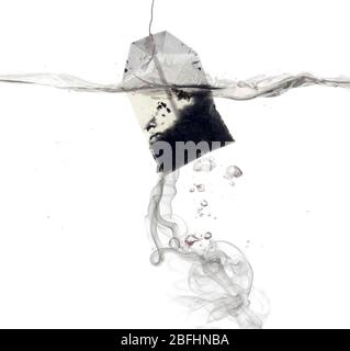 Tea bag dipped in hot water Stock Photo