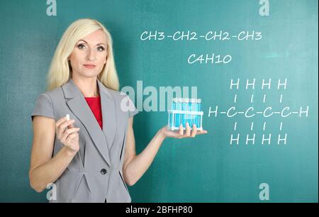 Chemistry teacher explaining formula written on blackboard to her pupils Stock Photo