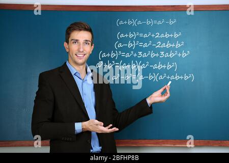 Teacher explaining formulas written on blackboard to  pupils Stock Photo