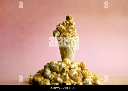 Caramel Popcorn in ice cream cone on pink colorful background. caramel Popcorn on a cone cornucopia. Splitted popcorn on bright hipster background Stock Photo