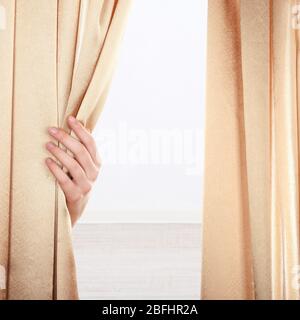 Hand opening curtain on wall background Stock Photo
