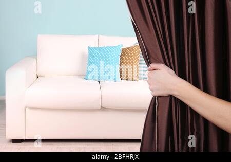 Hand opening curtain on room background Stock Photo
