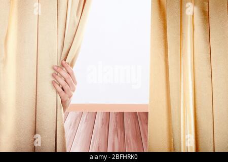 Hand opening curtain on room background Stock Photo
