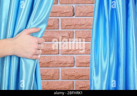 Hand opening curtain on wall background Stock Photo
