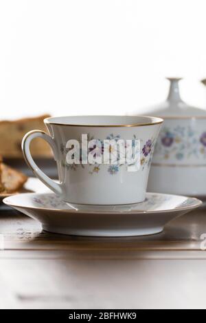 China tea set serving fruit cake. The set consists of tera cup and saucer preserve,jam pot with lid on table and would make a good menu image. Stock Photo