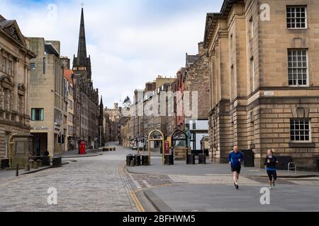Edinburgh, Scotland, UK. 18 April 2020. Views of empty streets and members of the public outside on another Saturday during the coronavirus lockdown in Edinburgh. The Royal Mile is empty apart from two runners. Iain Masterton/Alamy Live News Stock Photo