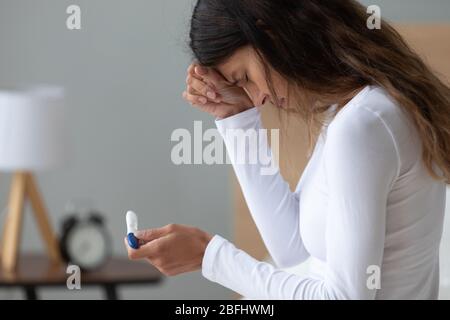 Unhappy stressed woman crying, feeling depressed, holding pregnancy test Stock Photo