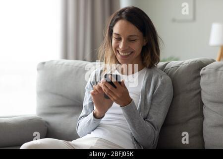 Happy laughing woman using phone, having fun at home Stock Photo