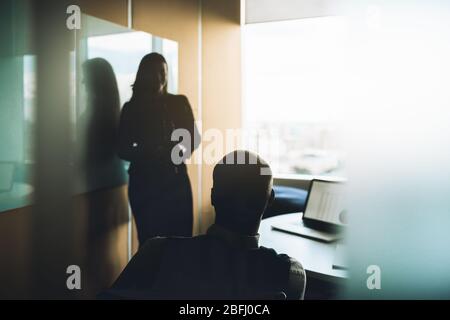 View of a modern cozy boardroom with business people having conference: selective focus on a silhouette of a sitting businessman who is listening a re Stock Photo