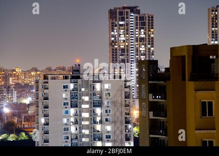 Aerial shot of buildings at night in Gurgaon with smaller buildings in front and skyscrapers in the background Stock Photo